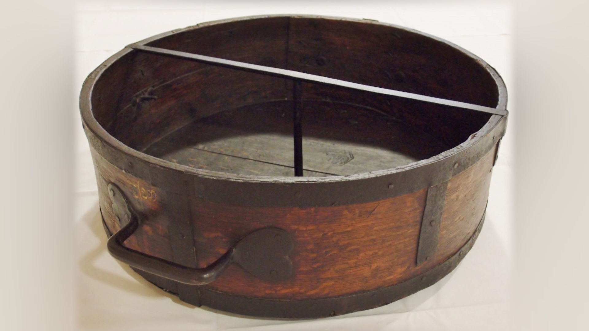 Foto: großes rundes Holzgefäß mit Metallbeschlägen.