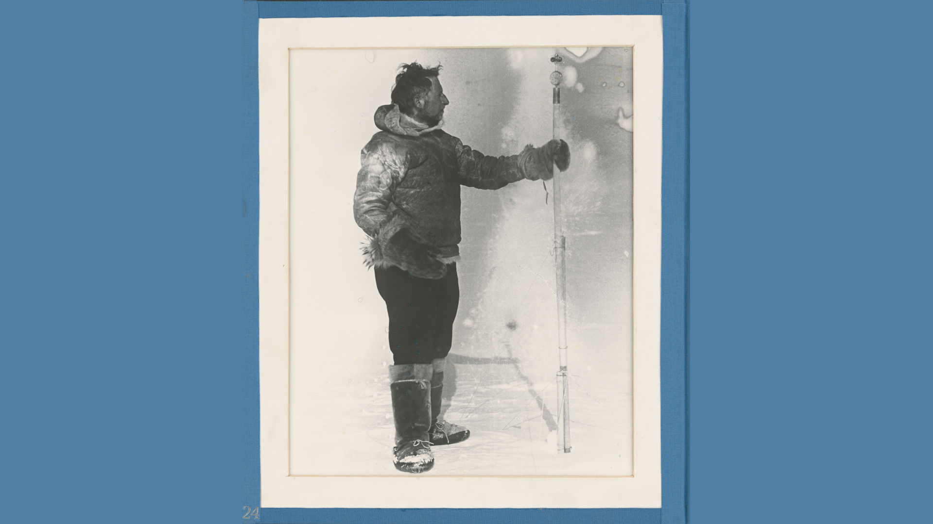 schwarz-weiß Foto: Mann mit Winterkleidung und einem senkrechten Stab in der Hand, auf den er blickt.